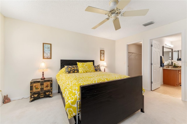 carpeted bedroom featuring a closet, a spacious closet, connected bathroom, a textured ceiling, and ceiling fan