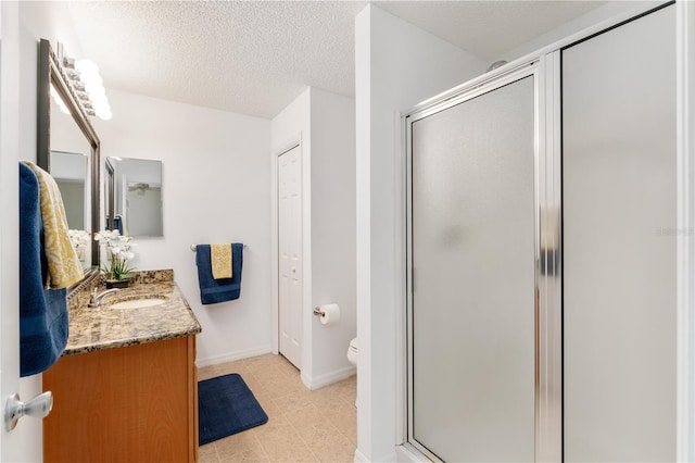 bathroom featuring toilet, vanity, a textured ceiling, and a shower with shower door