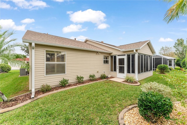 rear view of property with central AC unit, a sunroom, and a yard