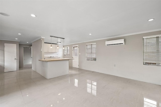 kitchen featuring kitchen peninsula, hanging light fixtures, a wall unit AC, white cabinets, and crown molding