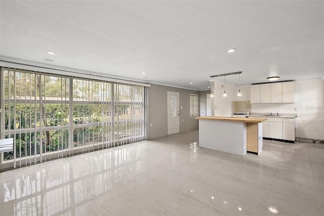 kitchen with a wealth of natural light, a center island, pendant lighting, and white cabinets