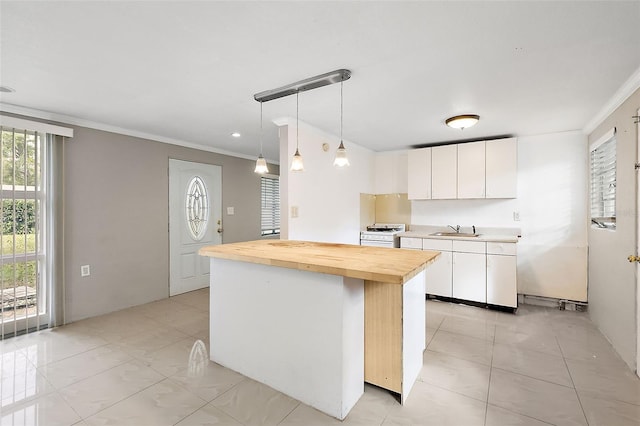 kitchen featuring butcher block countertops, a center island, white cabinetry, pendant lighting, and ornamental molding