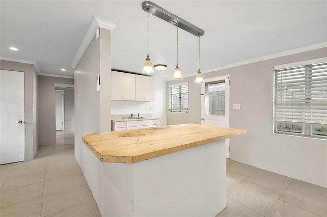 kitchen featuring plenty of natural light, white cabinetry, pendant lighting, and wood counters