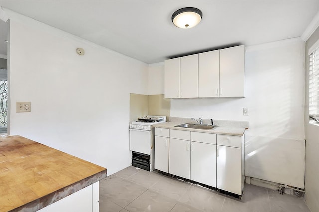 kitchen with white cabinetry, crown molding, sink, and gas range gas stove