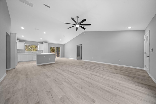 unfurnished living room with ceiling fan, sink, vaulted ceiling, and light wood-type flooring