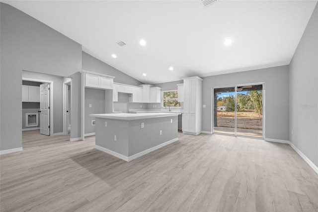 kitchen with white cabinetry, a center island, a kitchen breakfast bar, high vaulted ceiling, and light hardwood / wood-style floors