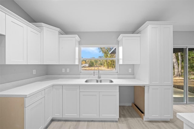 kitchen with white cabinets, light hardwood / wood-style floors, and sink