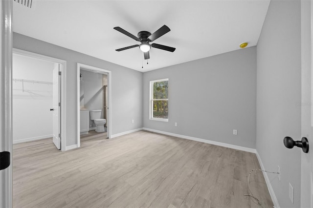 unfurnished bedroom with ensuite bath, ceiling fan, light hardwood / wood-style flooring, a walk in closet, and a closet