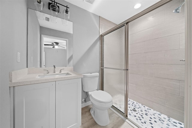 bathroom with ceiling fan, a shower with door, wood-type flooring, and toilet