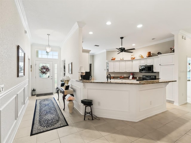 kitchen with dark stone counters, ceiling fan, crown molding, white cabinets, and black electric range oven