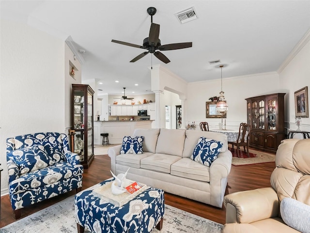 living room with hardwood / wood-style flooring, ceiling fan, ornate columns, and crown molding