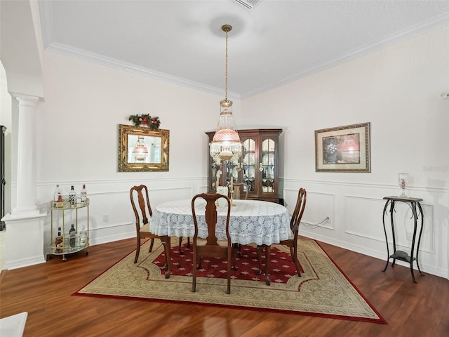 dining space featuring dark hardwood / wood-style flooring, decorative columns, and crown molding