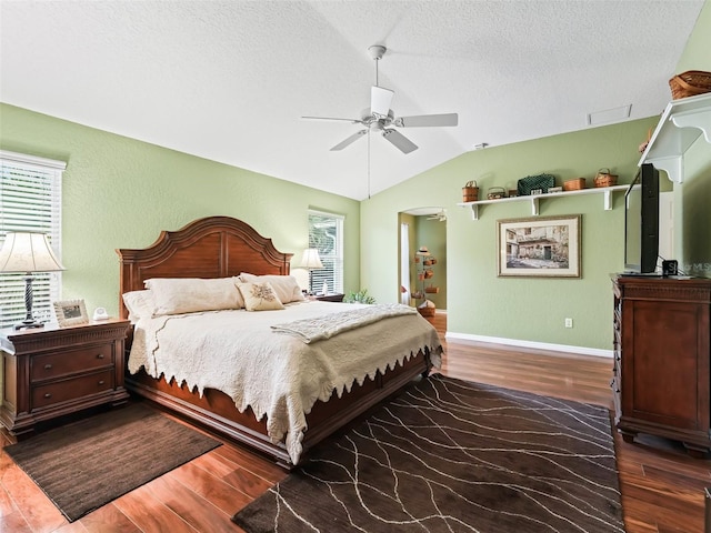 bedroom with ceiling fan, dark hardwood / wood-style flooring, a textured ceiling, and vaulted ceiling