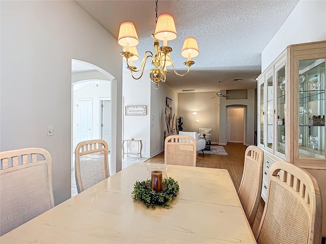 dining area featuring a textured ceiling, hardwood / wood-style floors, and ceiling fan with notable chandelier