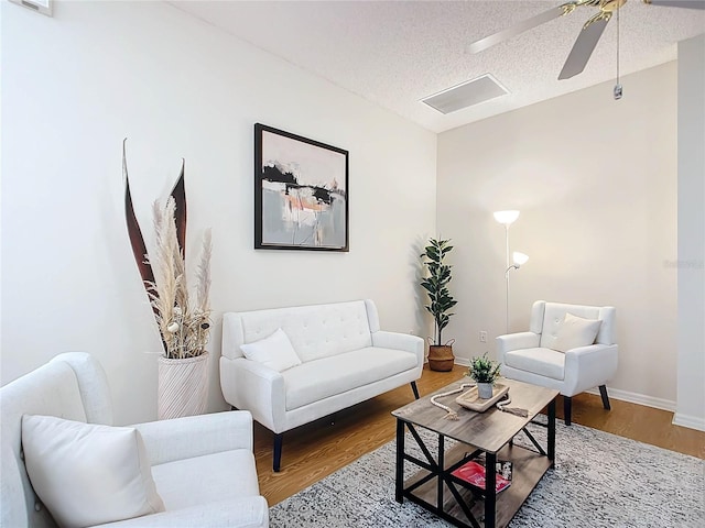 living room with hardwood / wood-style flooring, ceiling fan, and a textured ceiling