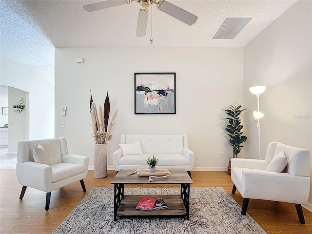 living room featuring light hardwood / wood-style floors, a textured ceiling, and ceiling fan