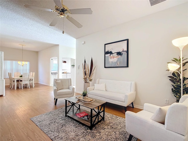 living room featuring wood-type flooring, a textured ceiling, and ceiling fan with notable chandelier