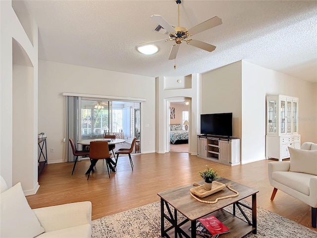 living room with a textured ceiling, hardwood / wood-style flooring, and ceiling fan