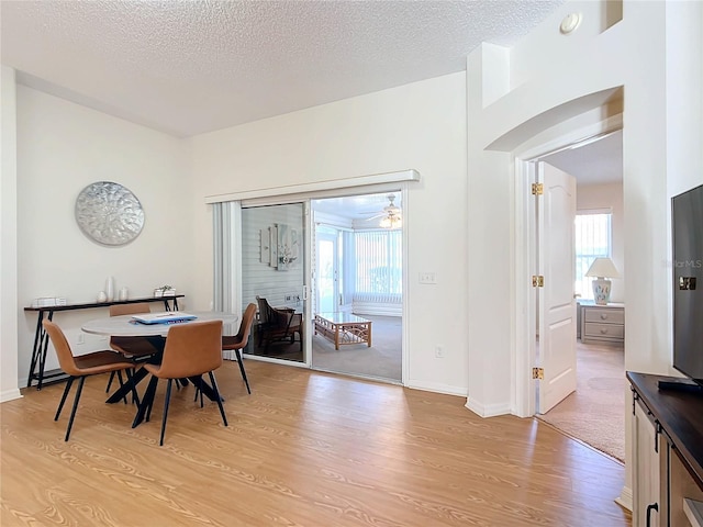 dining area featuring a textured ceiling, light wood-type flooring, and ceiling fan