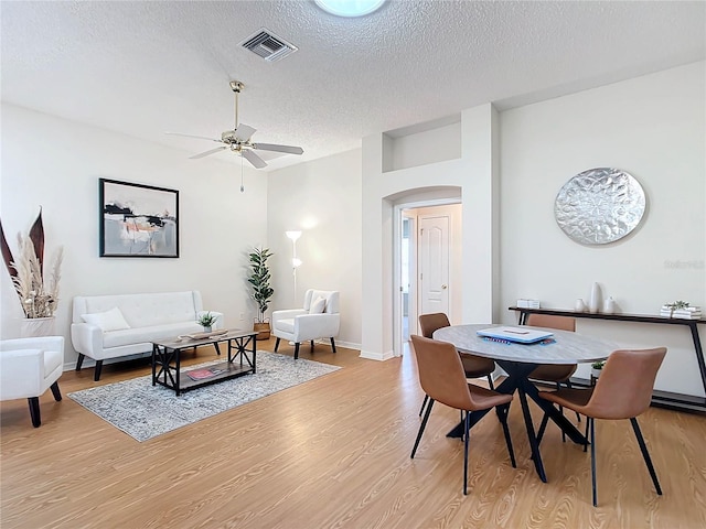 dining room featuring light hardwood / wood-style floors, a textured ceiling, and ceiling fan