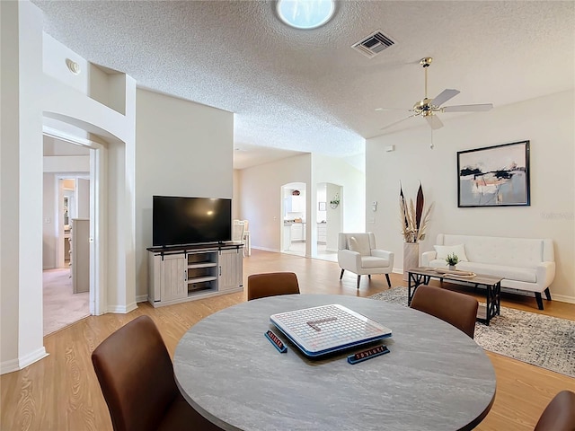 dining space with light hardwood / wood-style floors, ceiling fan, and a textured ceiling