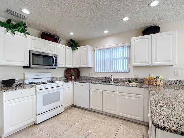 kitchen featuring light tile patterned flooring, sink, a textured ceiling, white appliances, and white cabinets