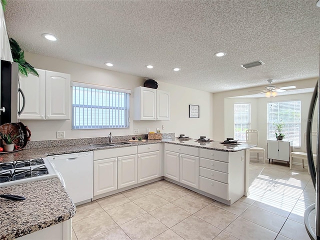 kitchen featuring white dishwasher, white cabinets, kitchen peninsula, a textured ceiling, and sink