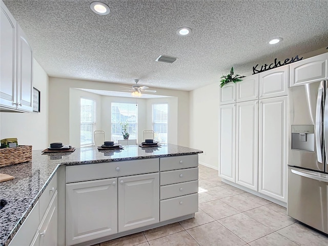 kitchen with dark stone countertops, white cabinetry, and stainless steel fridge with ice dispenser