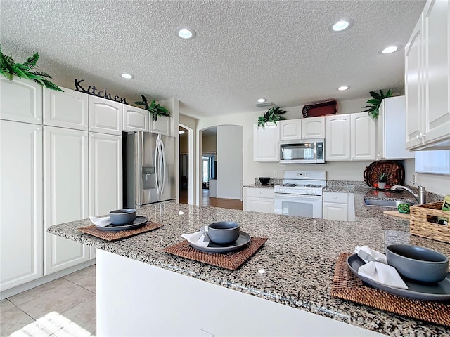 kitchen with white cabinetry, kitchen peninsula, stainless steel appliances, and a textured ceiling