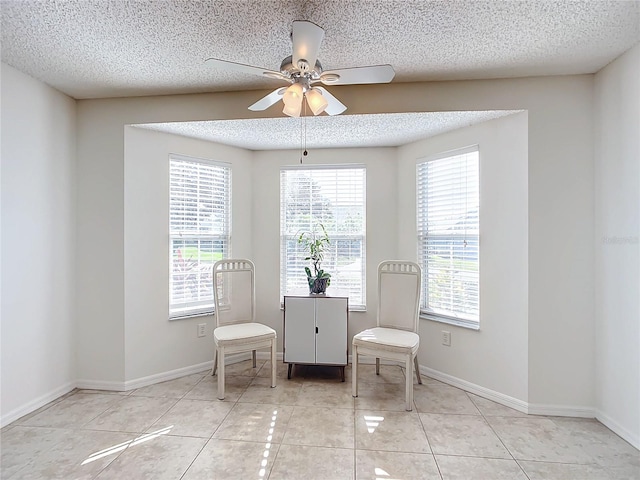 living area with a textured ceiling, light tile patterned flooring, and ceiling fan