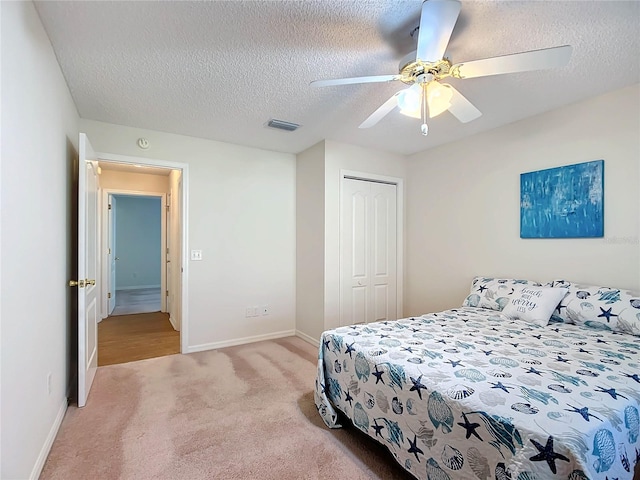 carpeted bedroom featuring a closet, a textured ceiling, and ceiling fan