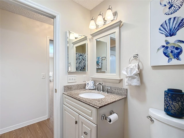 bathroom featuring toilet, vanity, hardwood / wood-style floors, and a textured ceiling