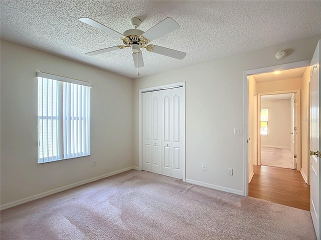 unfurnished bedroom with ceiling fan, multiple windows, a closet, and light colored carpet