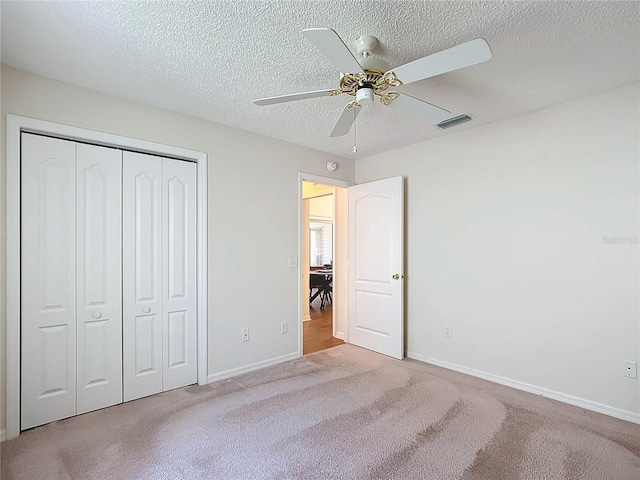 unfurnished bedroom featuring a textured ceiling, light carpet, ceiling fan, and a closet