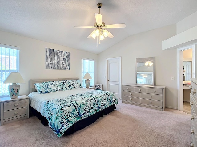 carpeted bedroom featuring vaulted ceiling, ceiling fan, multiple windows, and connected bathroom