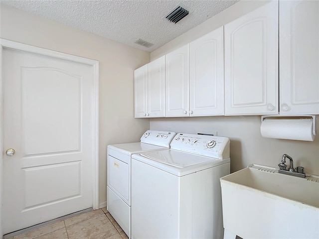 laundry room featuring cabinets, a textured ceiling, sink, and washer and dryer