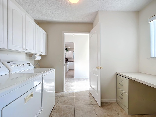 laundry area featuring cabinets, a textured ceiling, light tile patterned floors, and washing machine and clothes dryer