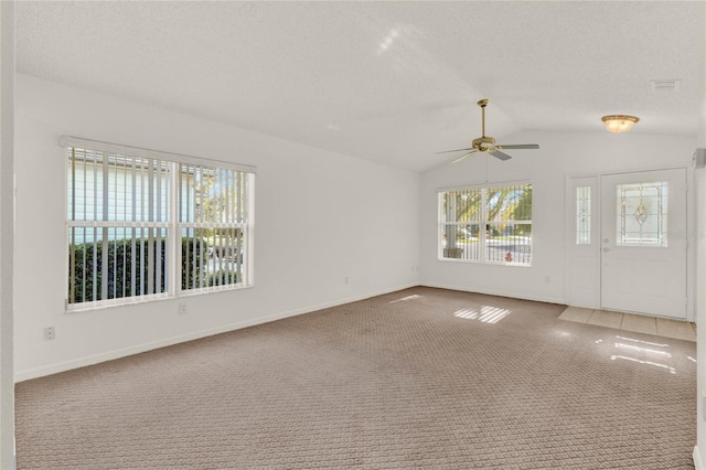 empty room featuring carpet floors, a textured ceiling, lofted ceiling, and ceiling fan