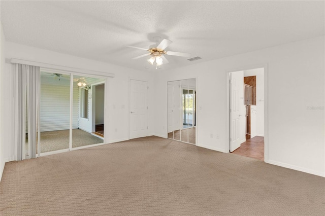 unfurnished room featuring a textured ceiling, ceiling fan, and carpet floors