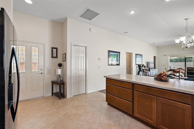 kitchen with light tile patterned floors, a notable chandelier, pendant lighting, and black fridge