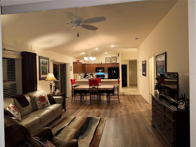 living room featuring vaulted ceiling, dark hardwood / wood-style flooring, and ceiling fan with notable chandelier