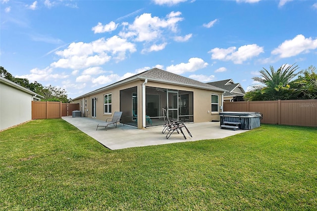 back of house featuring a hot tub, a patio area, a sunroom, cooling unit, and a yard