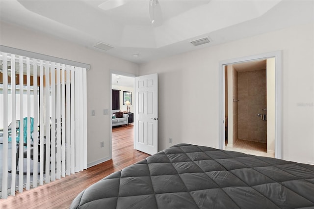 bedroom featuring ceiling fan, hardwood / wood-style floors, and a raised ceiling