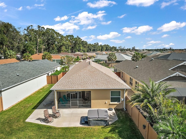 back of property with a sunroom, a hot tub, a lawn, and a patio