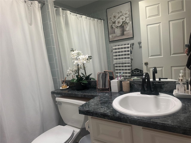 bathroom featuring toilet, vanity, and curtained shower