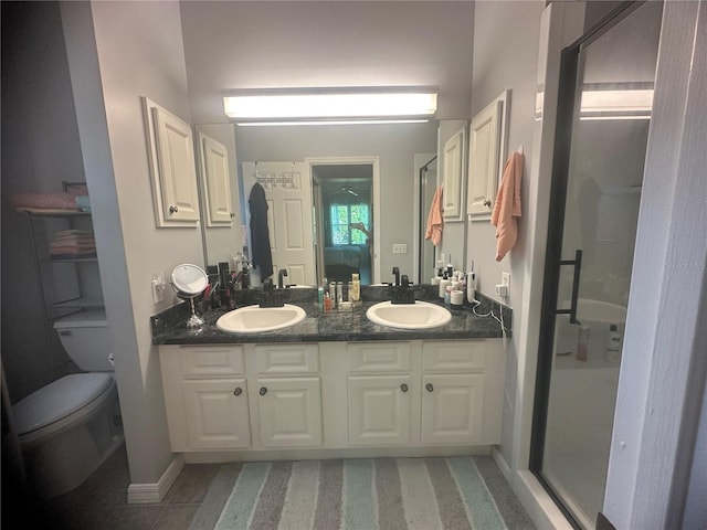 bathroom with tile patterned flooring, vanity, toilet, and a shower with shower door