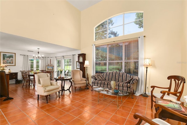 tiled living room featuring a towering ceiling, a wealth of natural light, and a notable chandelier