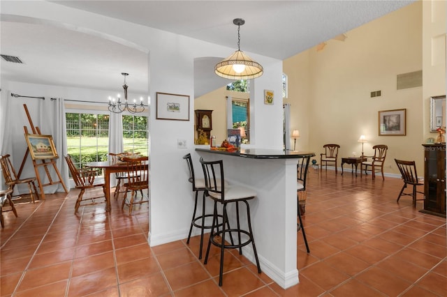 kitchen featuring pendant lighting, a breakfast bar, an inviting chandelier, tile patterned floors, and kitchen peninsula