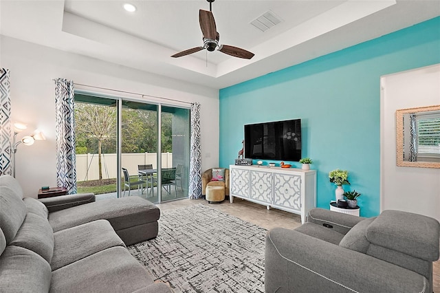 living room featuring ceiling fan and a raised ceiling