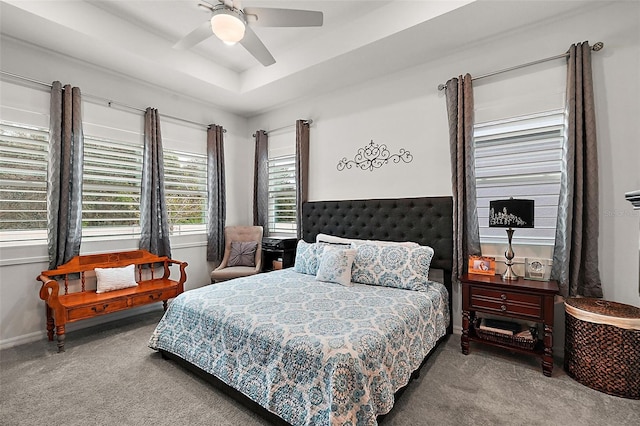 carpeted bedroom featuring ceiling fan and a tray ceiling